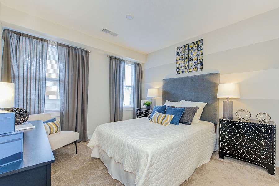 A bed with white comforter and blue pillows in a bedroom at Highpointe Apartments